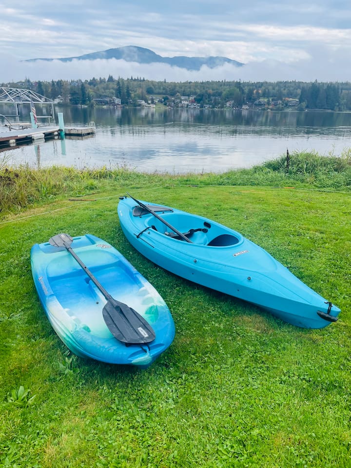Two kayaks, one adult and one child size, rest at the lake’s edge, ready for paddling adventures. The calm water and shoreline create an inviting setting for family fun on the lake.