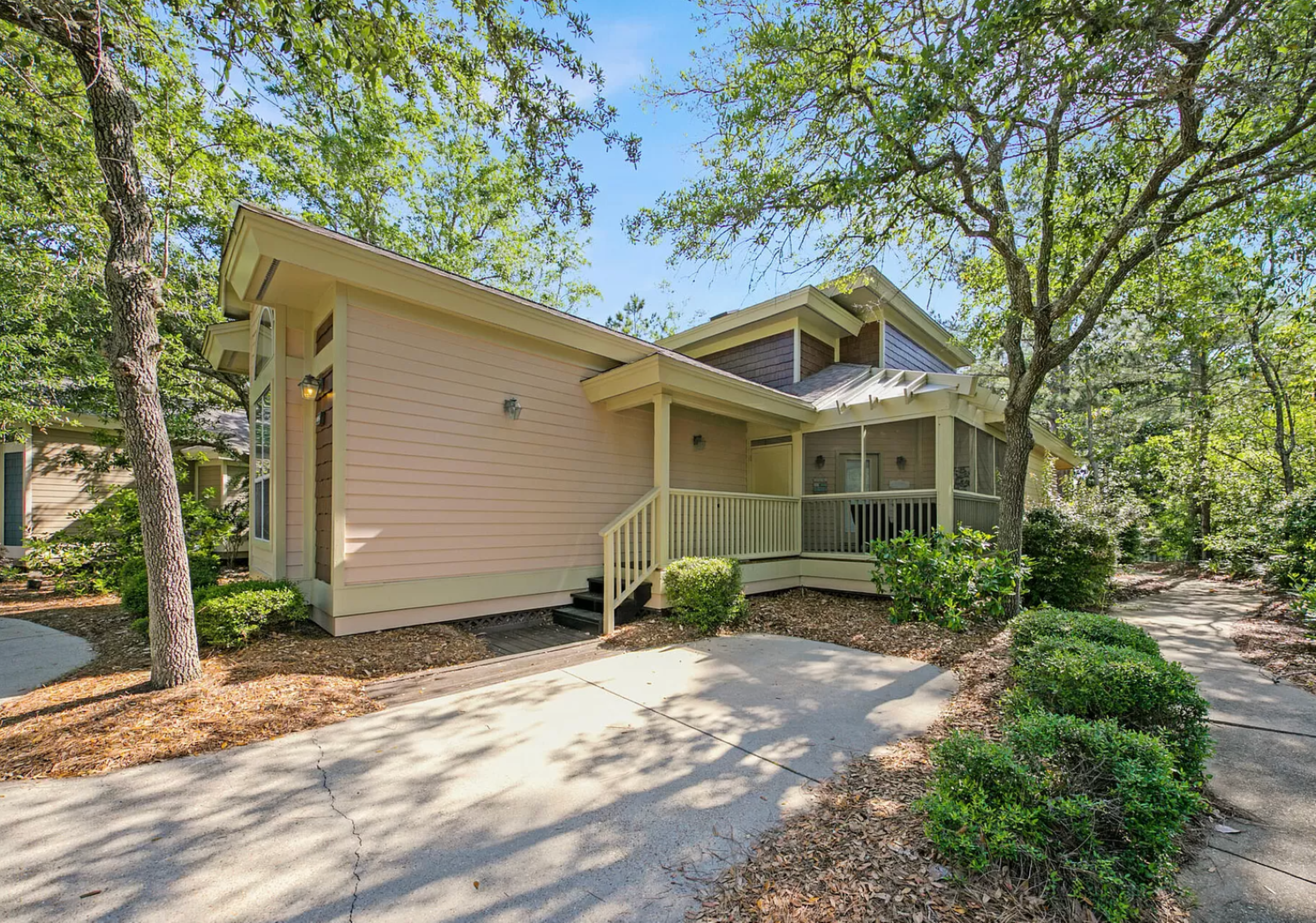Cozy, sunlit entrance to Bayside Bliss—a charming corner, soft coastal hues, and lush landscaping set the tone for a relaxed.