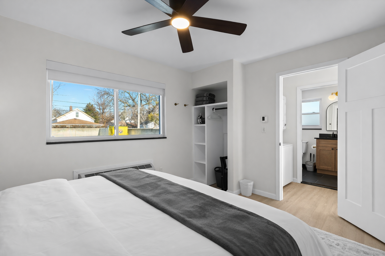 Spacious bedroom with a plush bed, ceiling fan, open storage, and direct access to the bathroom—designed for comfort, convenience, and a relaxing stay.