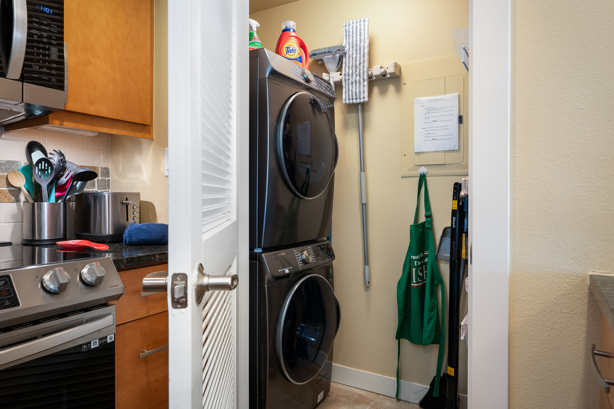 Modern stackable washer/dryer in pantry, with ample shelves to the right side for grocery items.