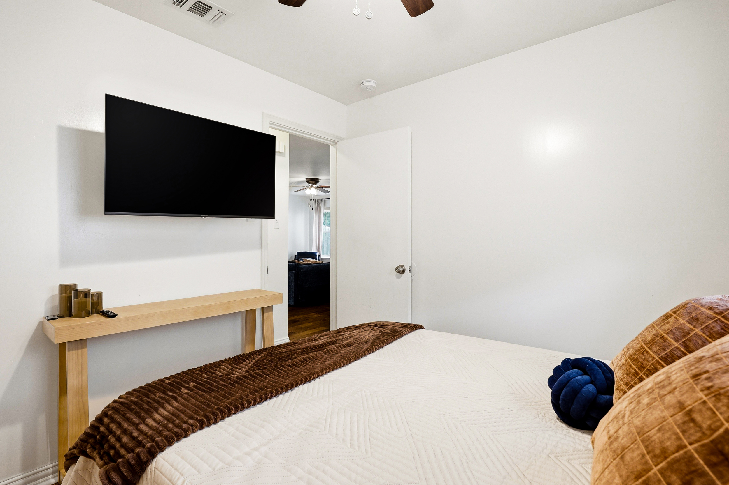 Double bedroom with velvet bedding, chest of drawers, ceiling fan, natural light, and Smart TV. Warm, well-decorated space with nightstands and closet — private and restful for couples or solo travelers.