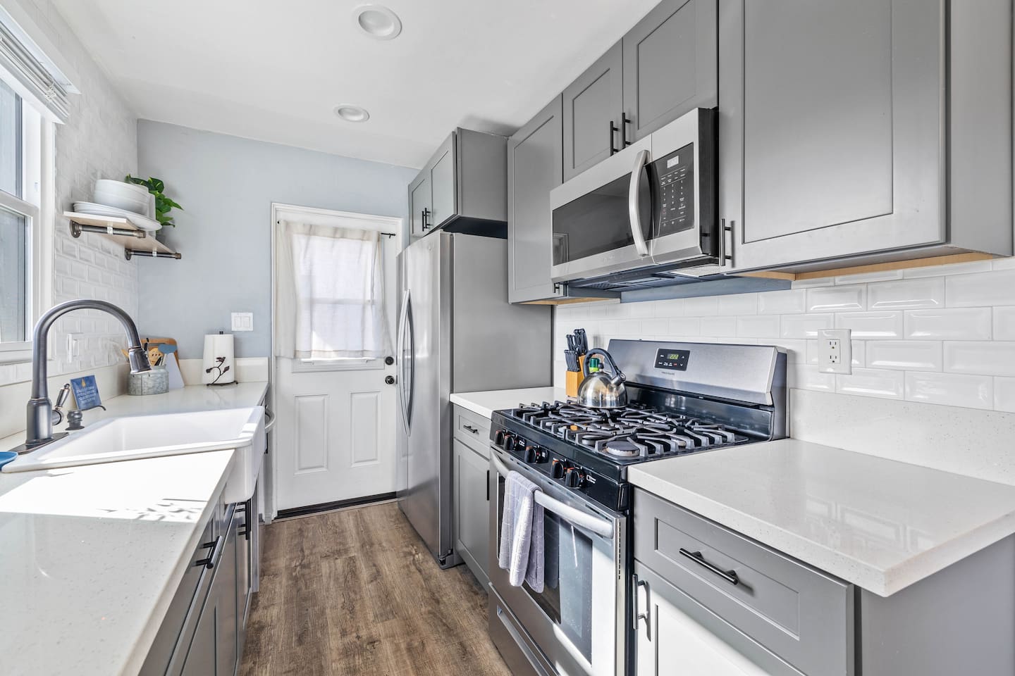 Cook in style in this modern kitchen, featuring a stove with a microwave above and an oven below, plus a sleek refrigerator and coffee maker. Fully stocked with neatly arranged plates, cups, and utensils, it's perfect for all your culinary adventures