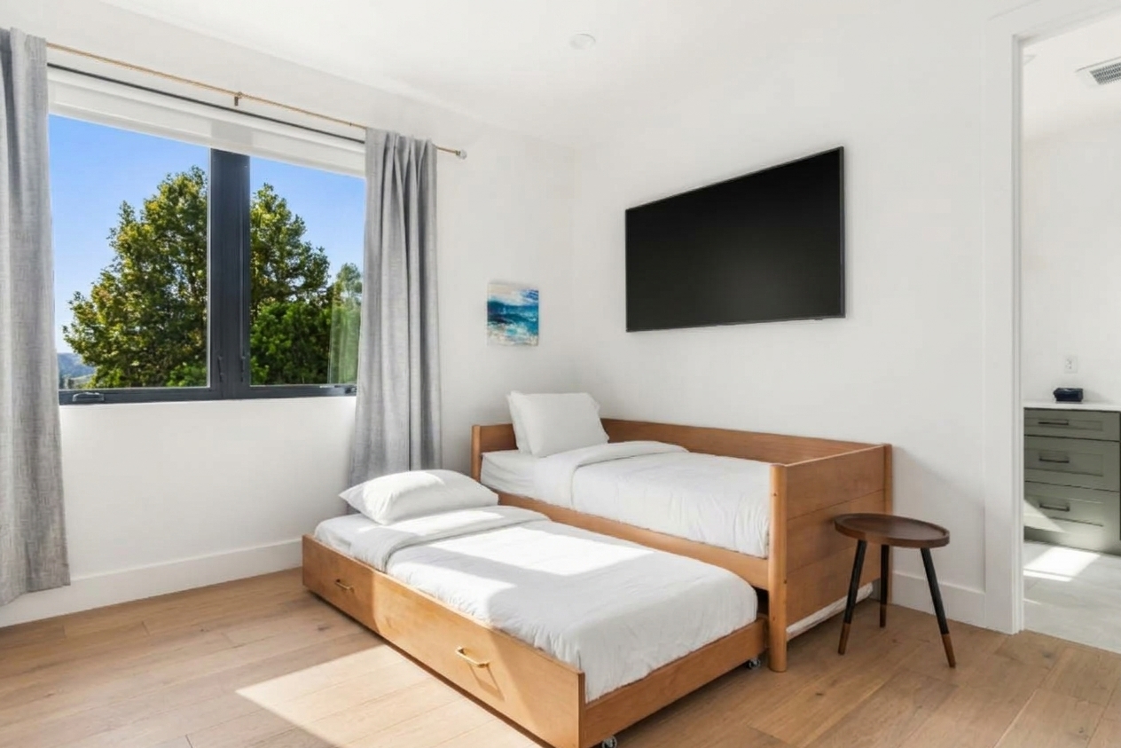 A cozy twin bed nook with twin pullout trundle under mounted TV, tucked in the primary suite.