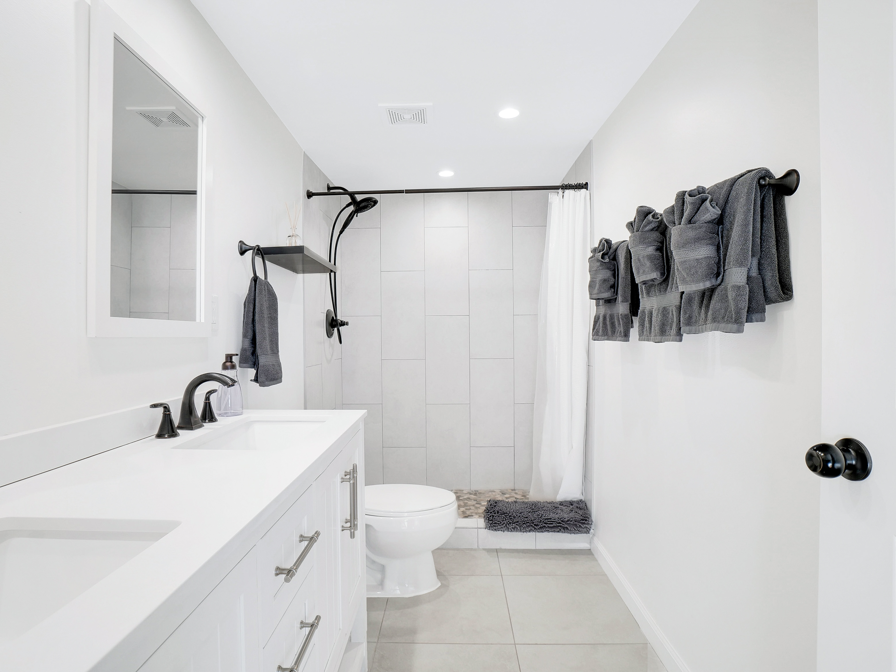 Primary bathroom with dual sinks and walk-in tile shower