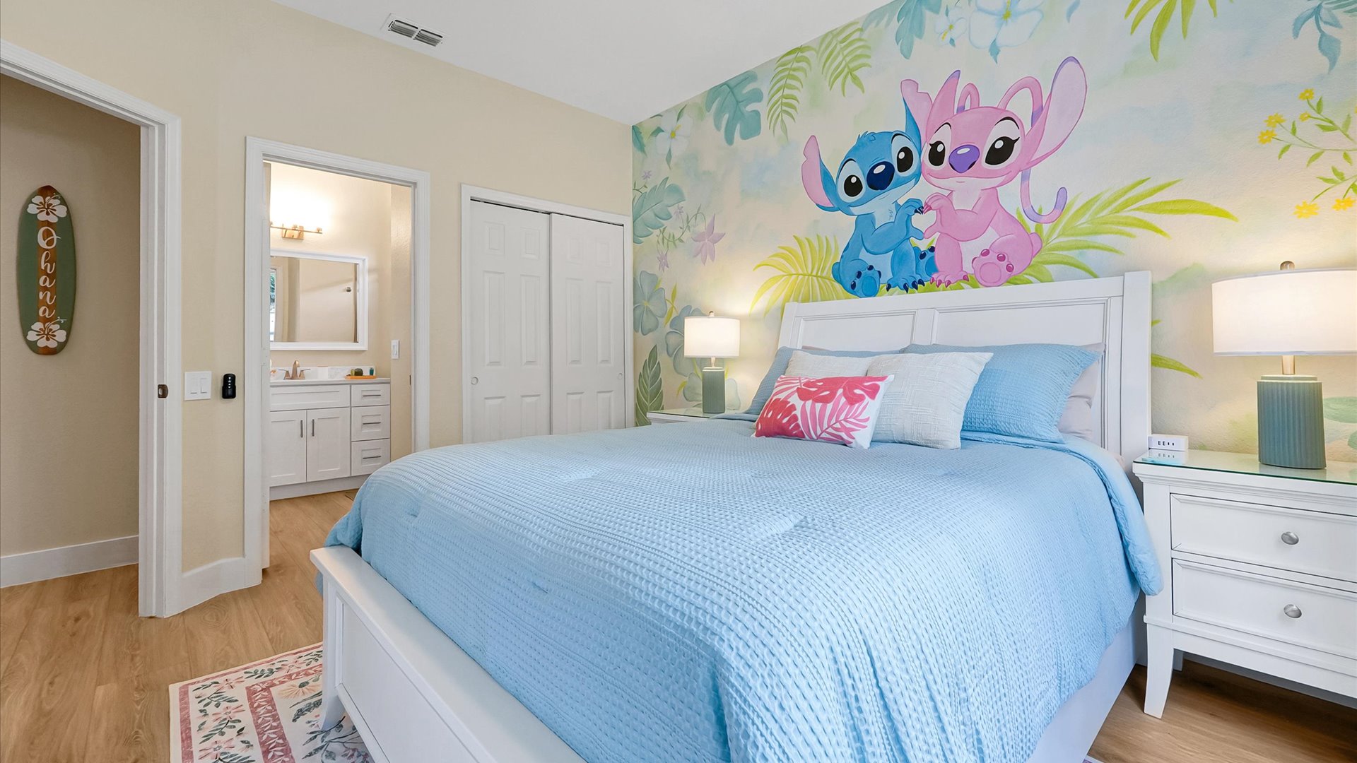 Stitch Queen Retreat: Main-floor queen bedroom with a hand-painted Stitch and Angel tropical mural, TV and abundant natural light.