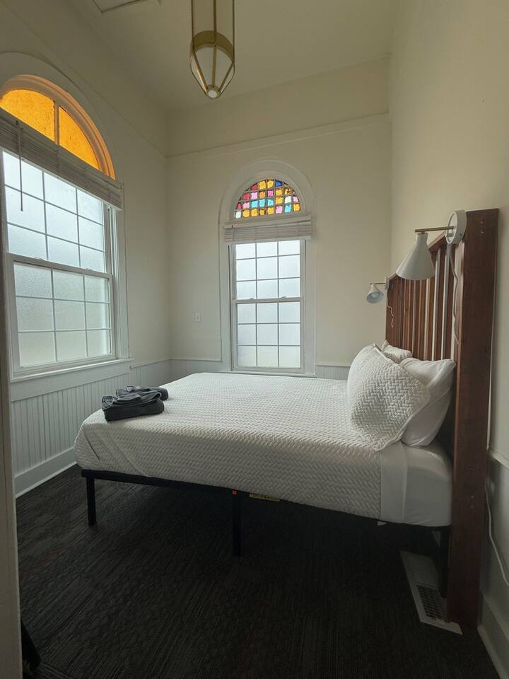 Bright and stylish front bedroom offering a queen bed, premium bedding, gentle lighting, and convenient essentials to make you feel at home.