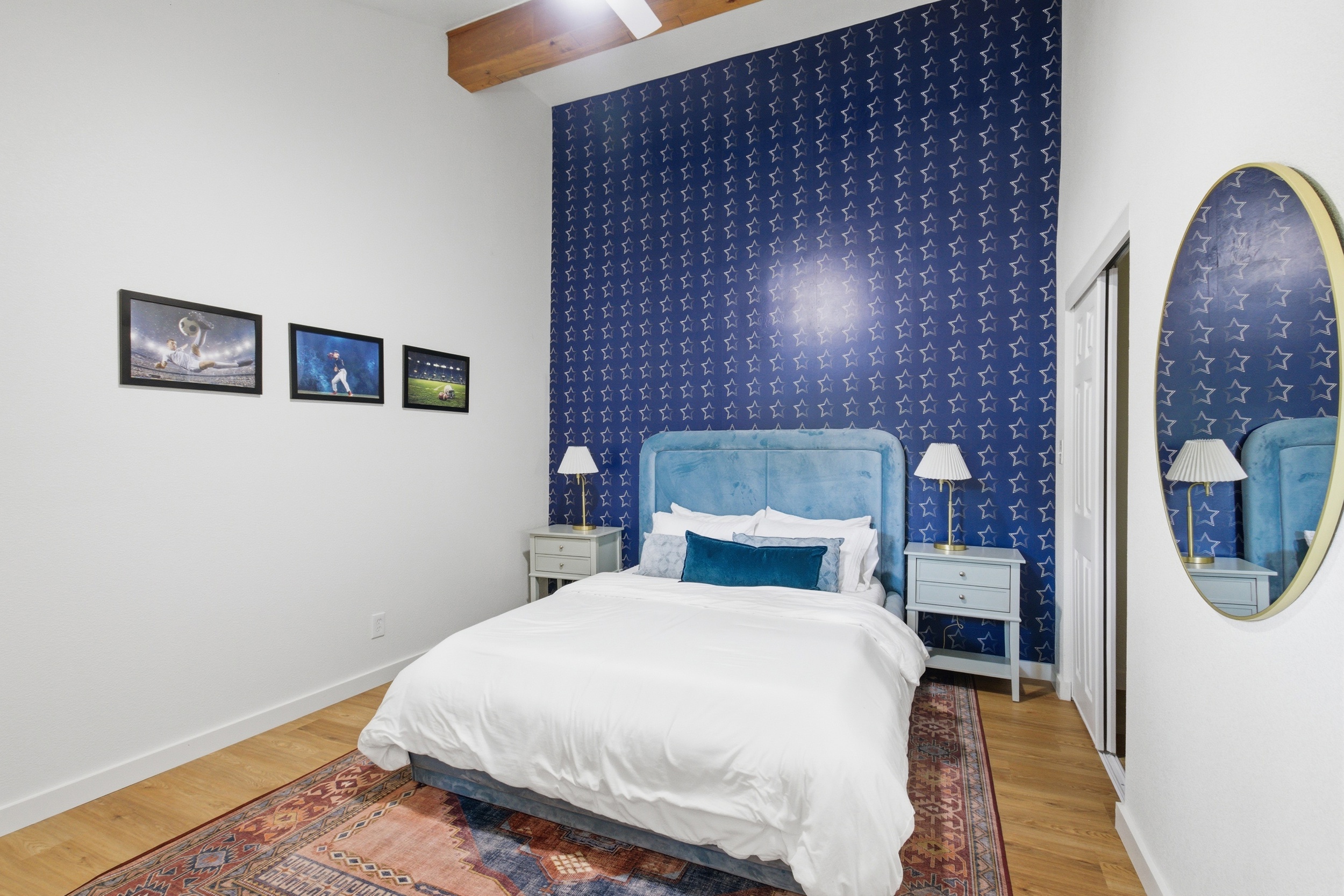 Double bed with navy accent wall, oval mirror, and classic table lamps. Room-darkening shades and lock on door included. Clothing storage throughout.