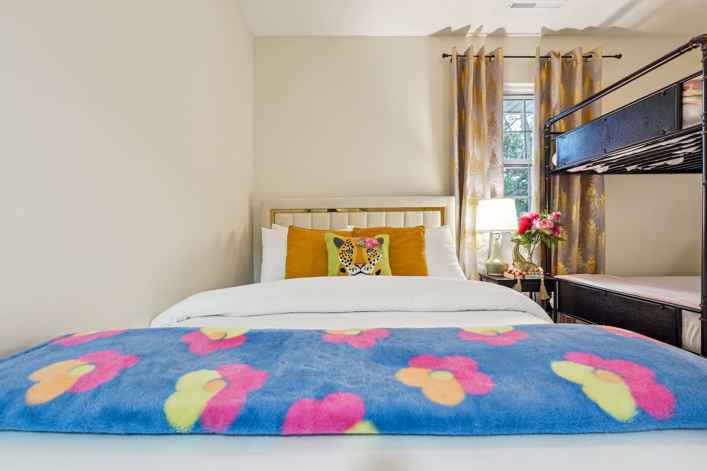 A cozy bedroom featuring a double bed, a bunk bed, a window, a bedside shelf with a lamp, and a TV — perfect for families or groups to relax and unwind.

