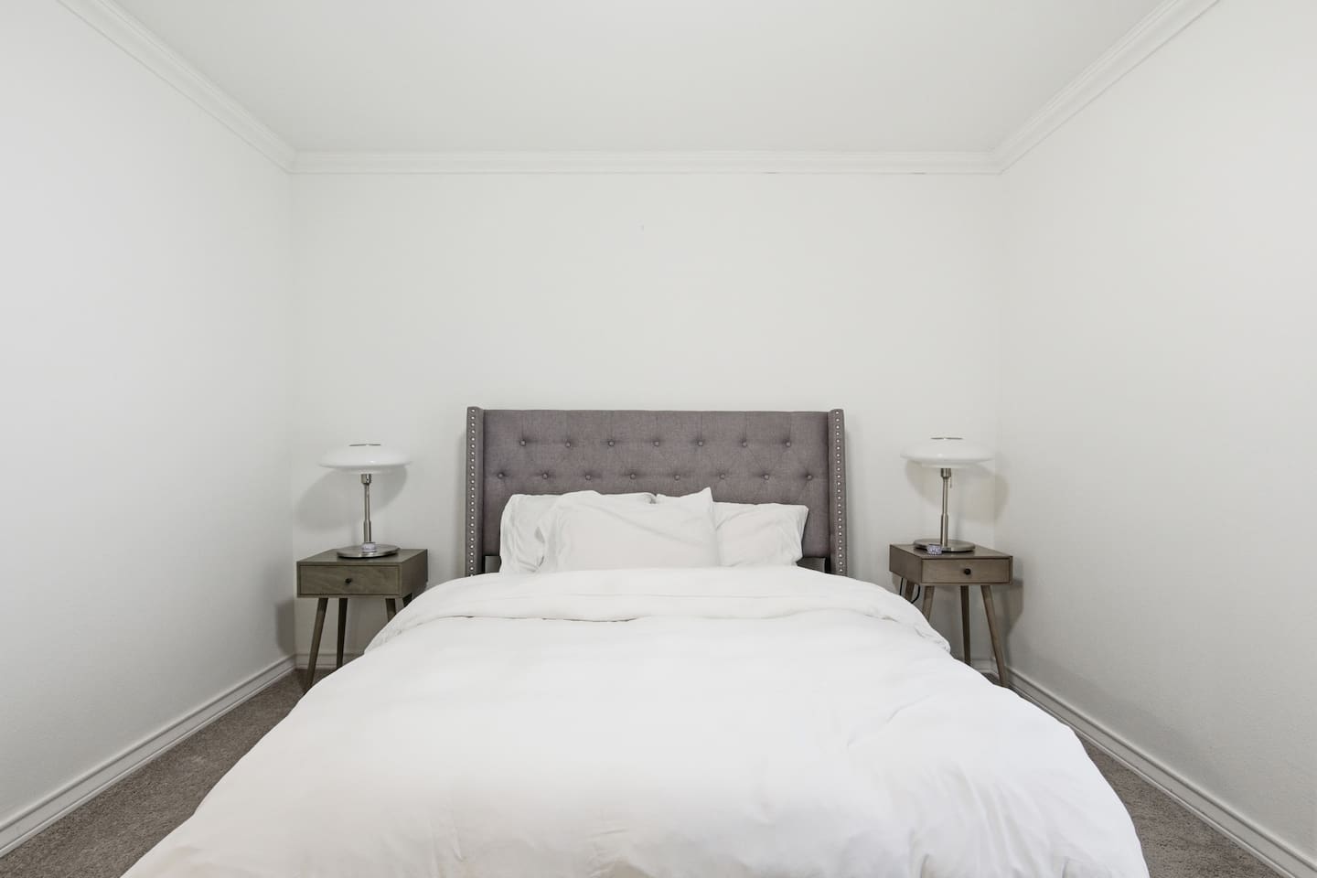 Spacious queen bedroom featuring soft bedding, bedside tables, clothing storage, TV, and room darkening shades for comfort and privacy.