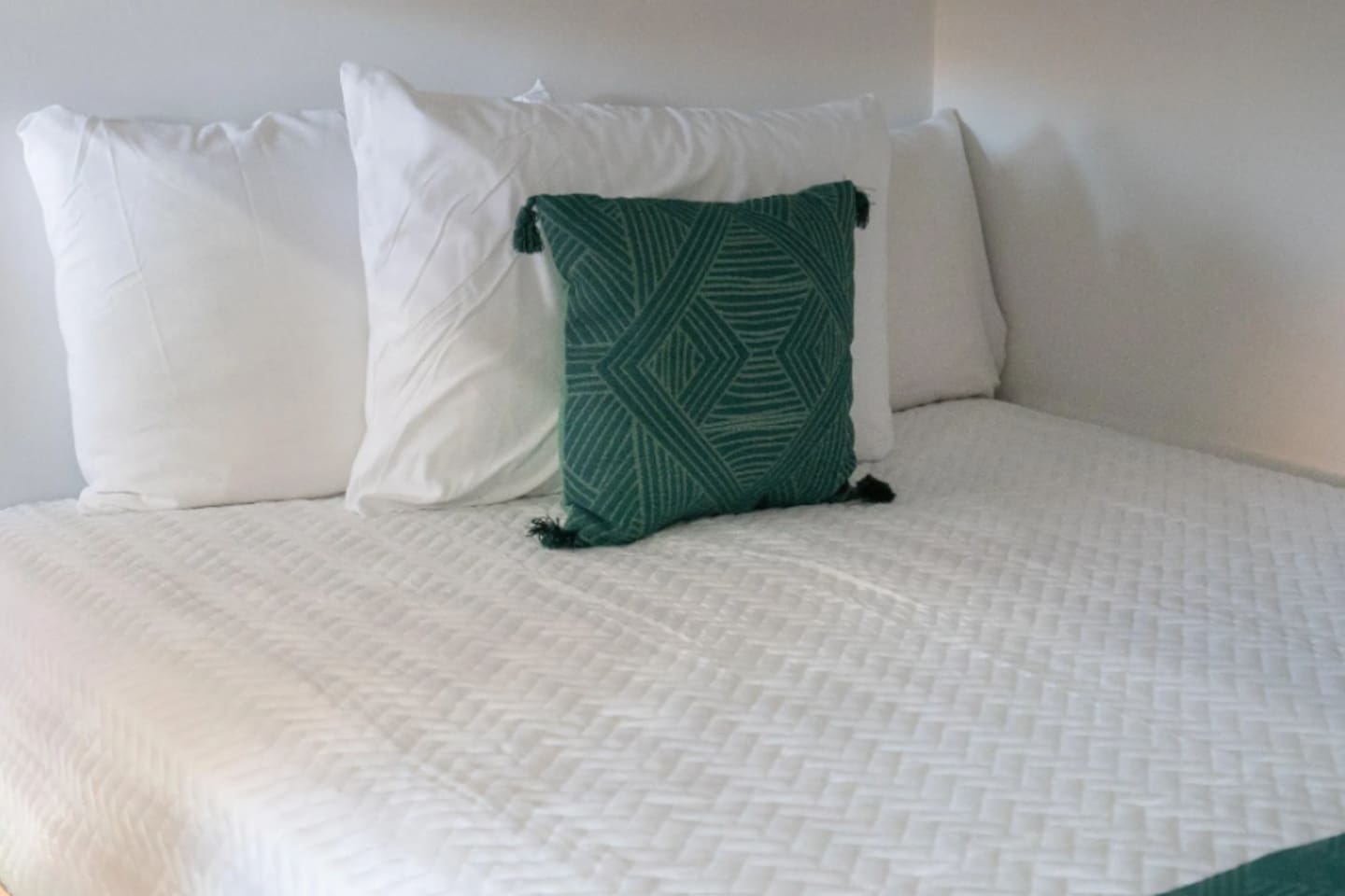 Crisp white linens get a pop of personality from a hand-woven, tasseled accent pillow, keeping the space playful without losing that put-together feel.

