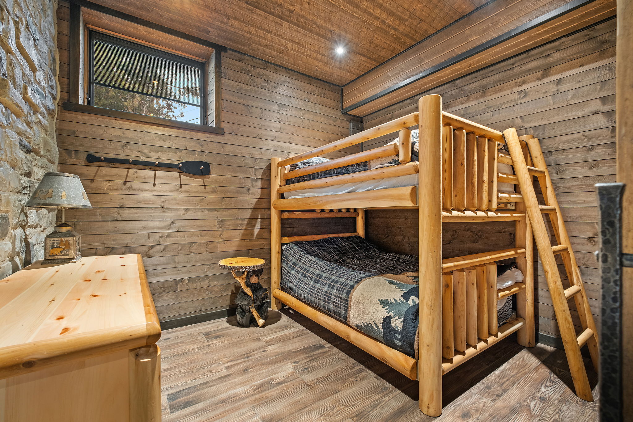 Spacious bunk room with a hand-built double-over-double log bunk bed — perfect for kids, teens, or groups. Cabin décor and natural wood finishes complete the atmosphere.