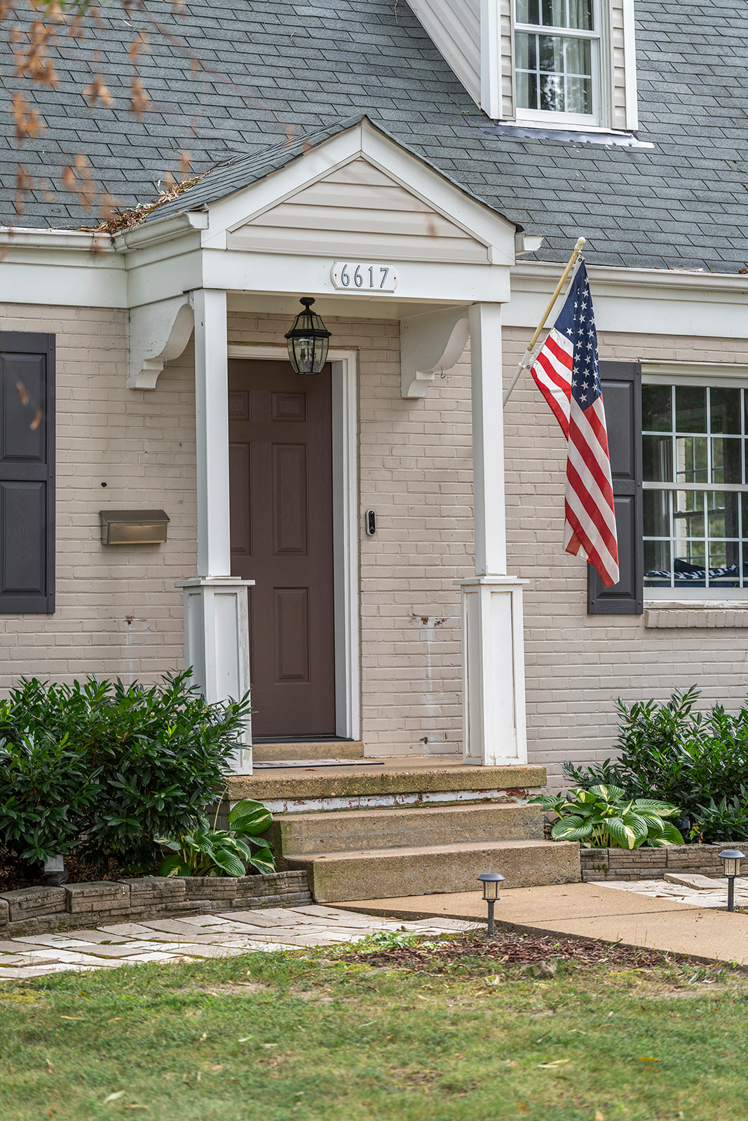 Charming Entrance: Step into this classic home with inviting landscaping and a welcoming flag display!