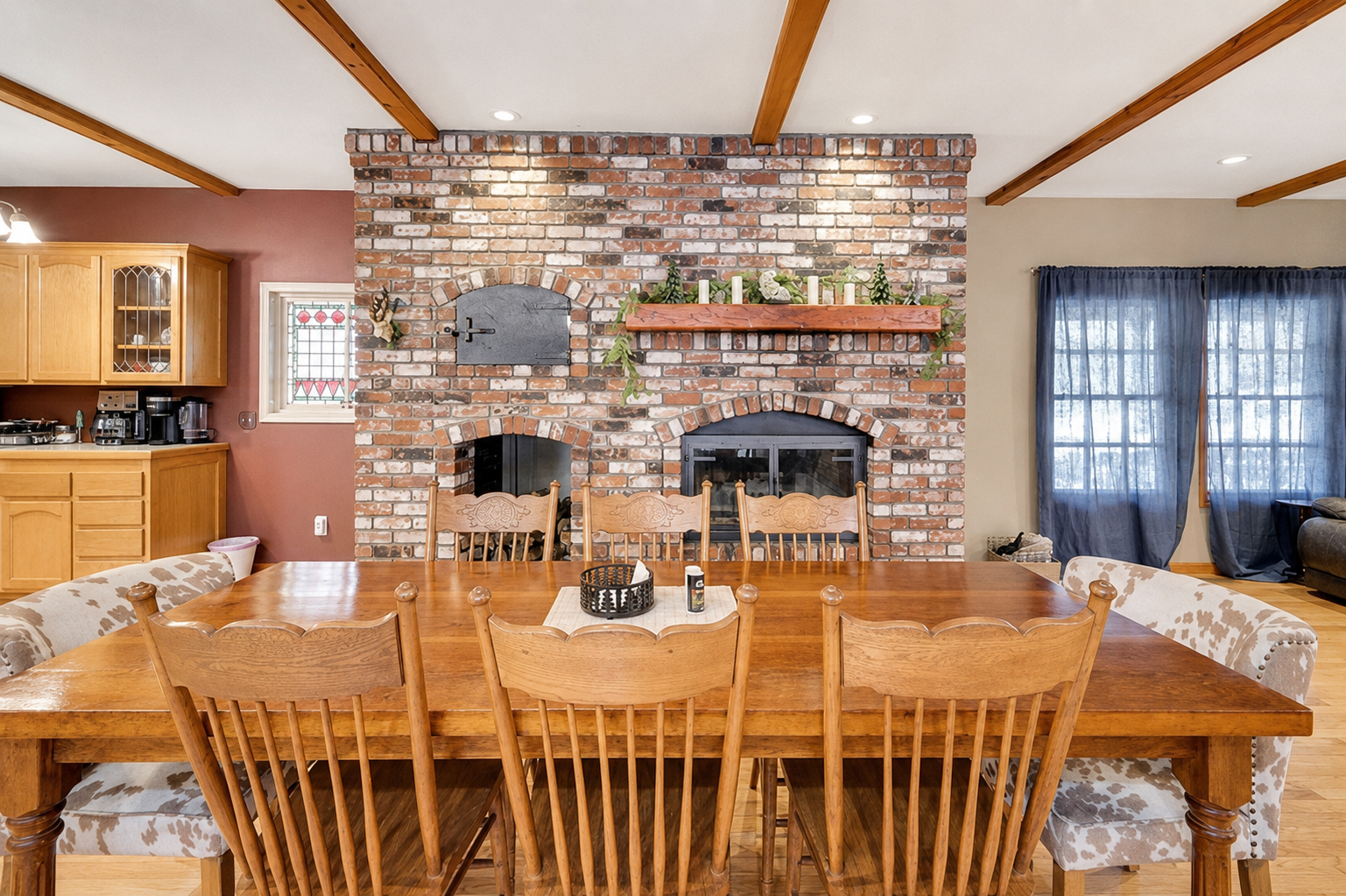 Dining area with large table seating, brick fireplace backdrop, and warm cabin-style details for shared meals.
