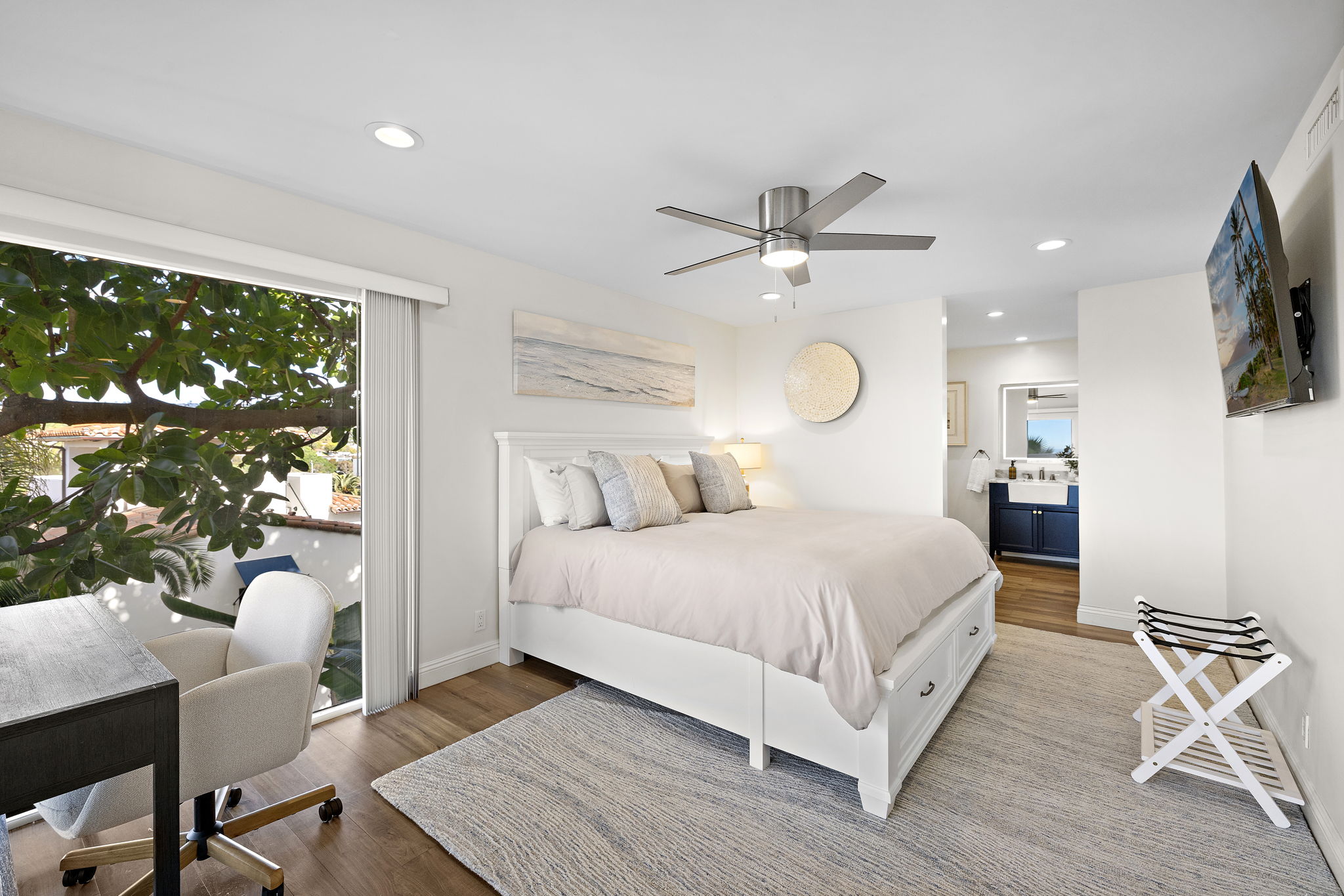 Spacious primary bedroom with luxury bedding, calming coastal design, and a connected en-suite bathroom—creating a private, comfortable retreat for restful nights and easy mornings