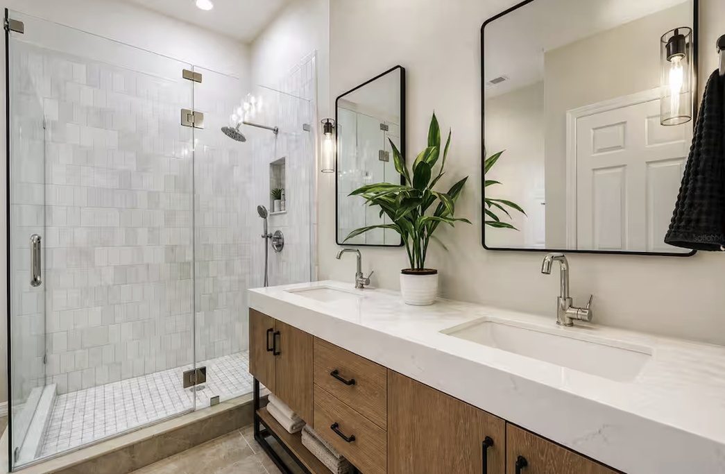 Modern and spacious bathroom featuring a large walk-in glass shower and double vanity with sleek finishes. Bright lighting and clean design create a fresh, spa-like space for your daily routine.