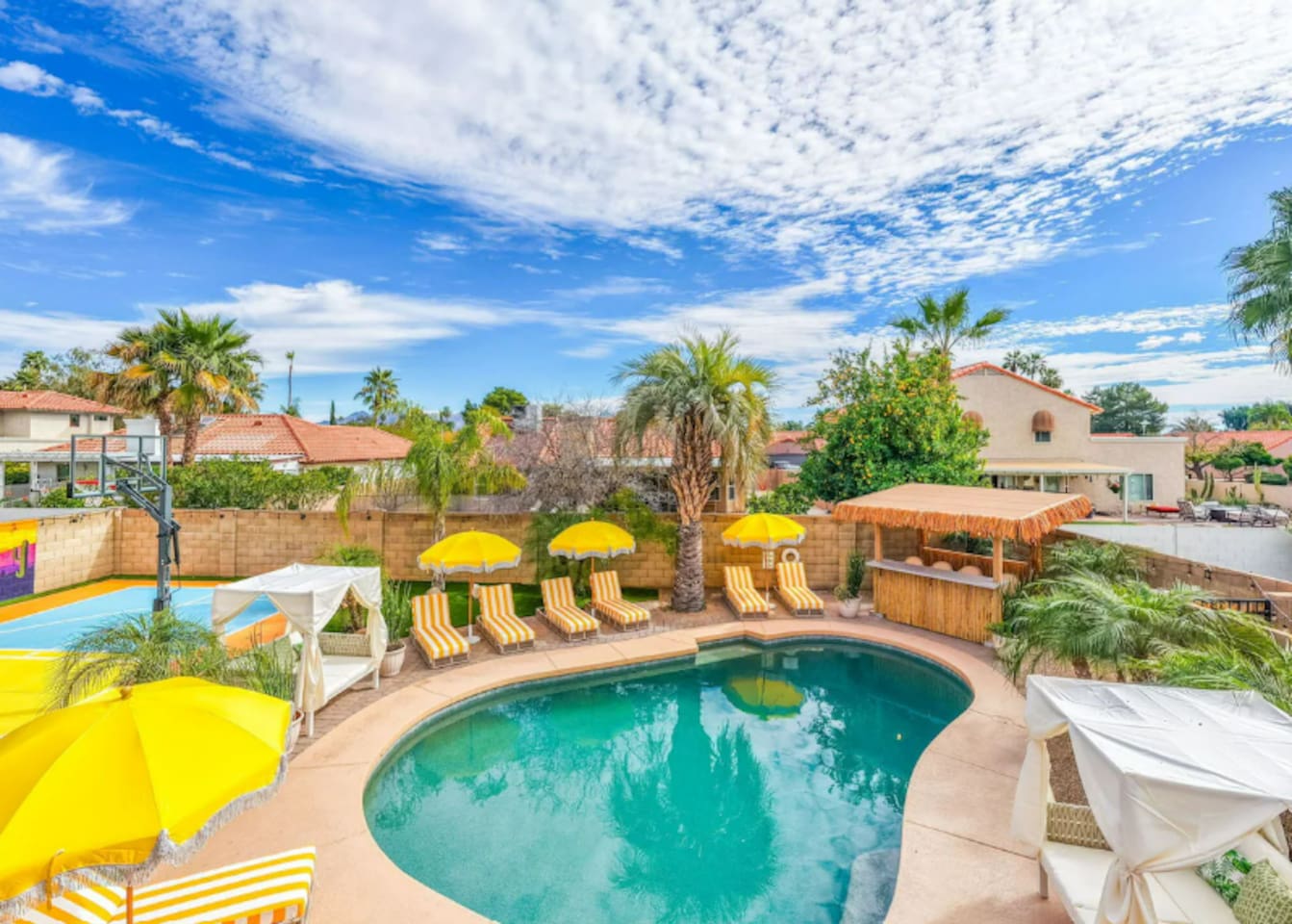 Resort-style pool area with loungers, yellow umbrellas, and desert views—a vacation oasis steps from the home.