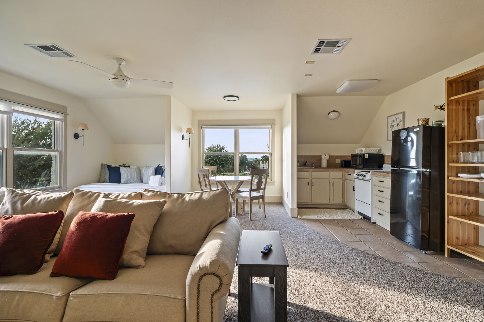 A private and spacious apartment above the garage featuring a queen daybed, a TV, two armchairs, and a three-person sofa for comfortable lounging.
