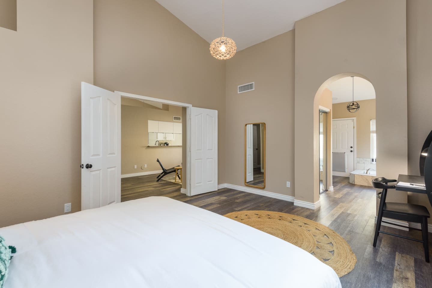 Primary ensuite bedroom with a spacious bed, dedicated workspace, high ceilings, and a bright, open layout for a comfortable stay.