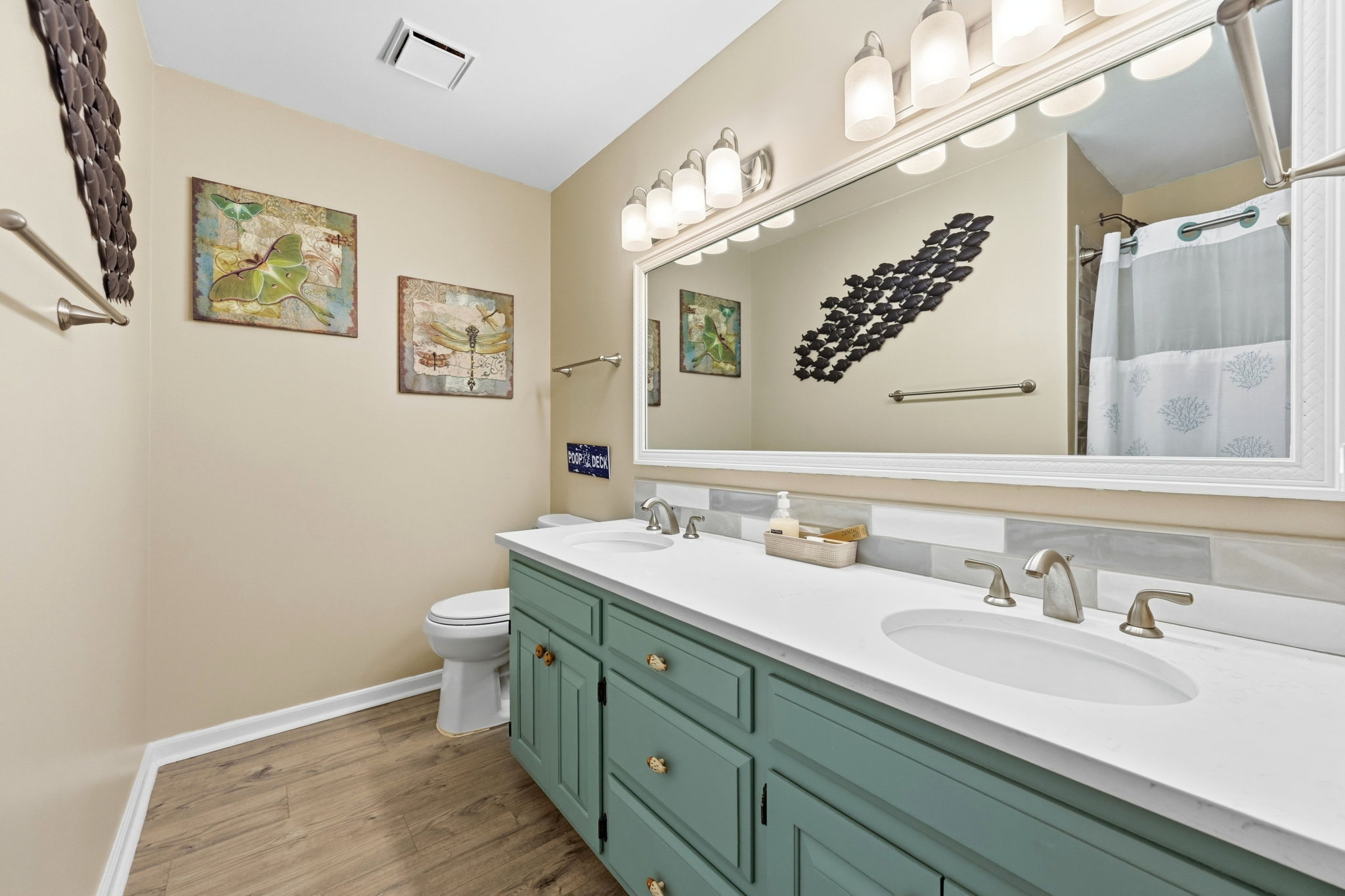 A spacious guest bathroom featuring double sinks and a convenient shower/tub combo.