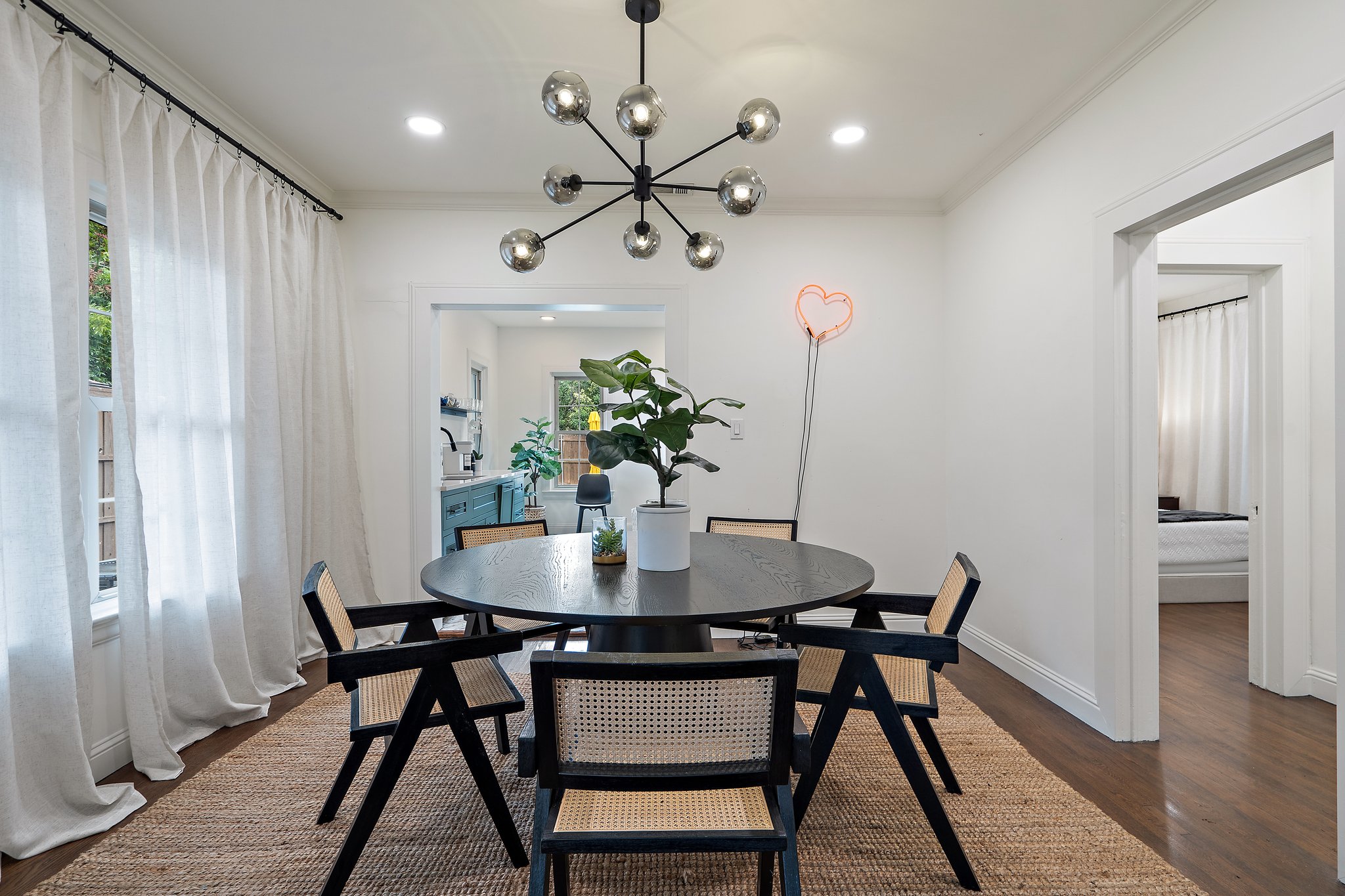 Dining area with round table, statement sputnik pendant chandelier, and seating for 6. Open flow to the fully equipped kitchen and living room. Main house, first floor.