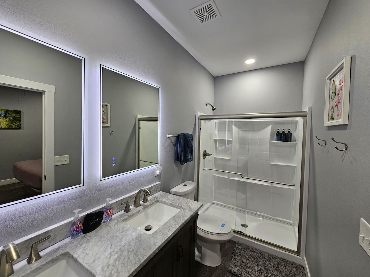 Clean and inviting bathroom with walk in shower, backlit mirrors, and fresh linens provided for your stay.