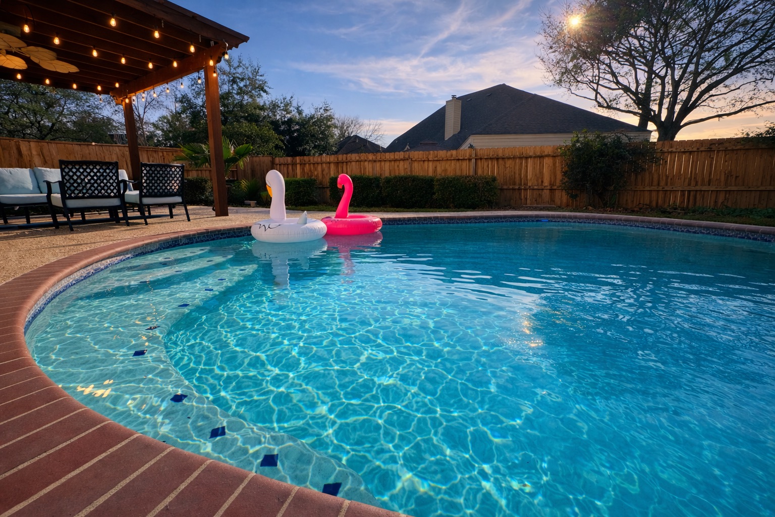 Private backyard oasis featuring a sparkling pool, shaded pergola lounge, and privacy fence — ideal for relaxing or entertaining.