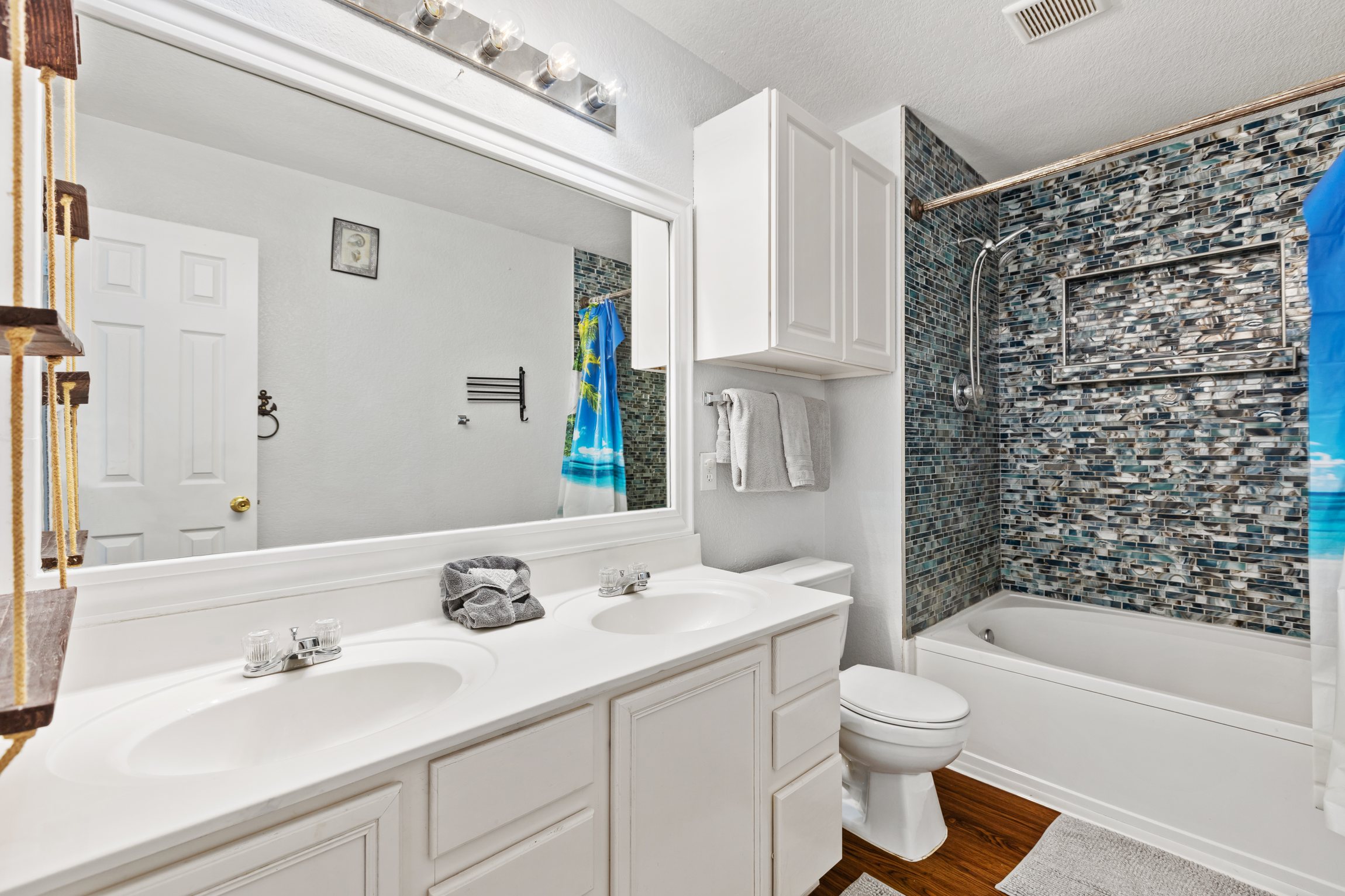 Upstairs bathroom with double sink vanity and stone tile shower and bath tub. Stocked with Ginger Lily Farms toiletries. Fresh towels provided. Built to handle the morning rush for groups of up to 10 guests.
