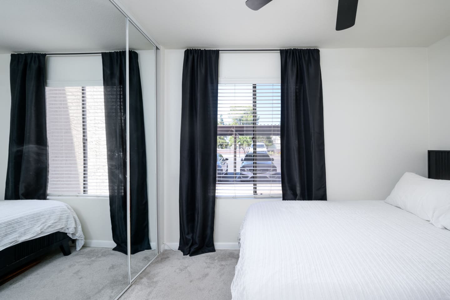 Bedroom with queen bed, dedicated workspace, ceiling fan, and a simple setup for rest or remote work.