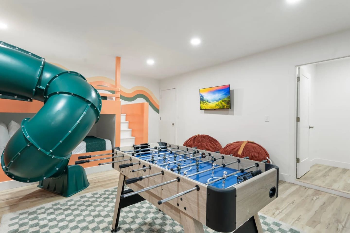 Another angle of the game room shows just how much is packed in here, from the slide to a mounted TV for background entertainment during game time.