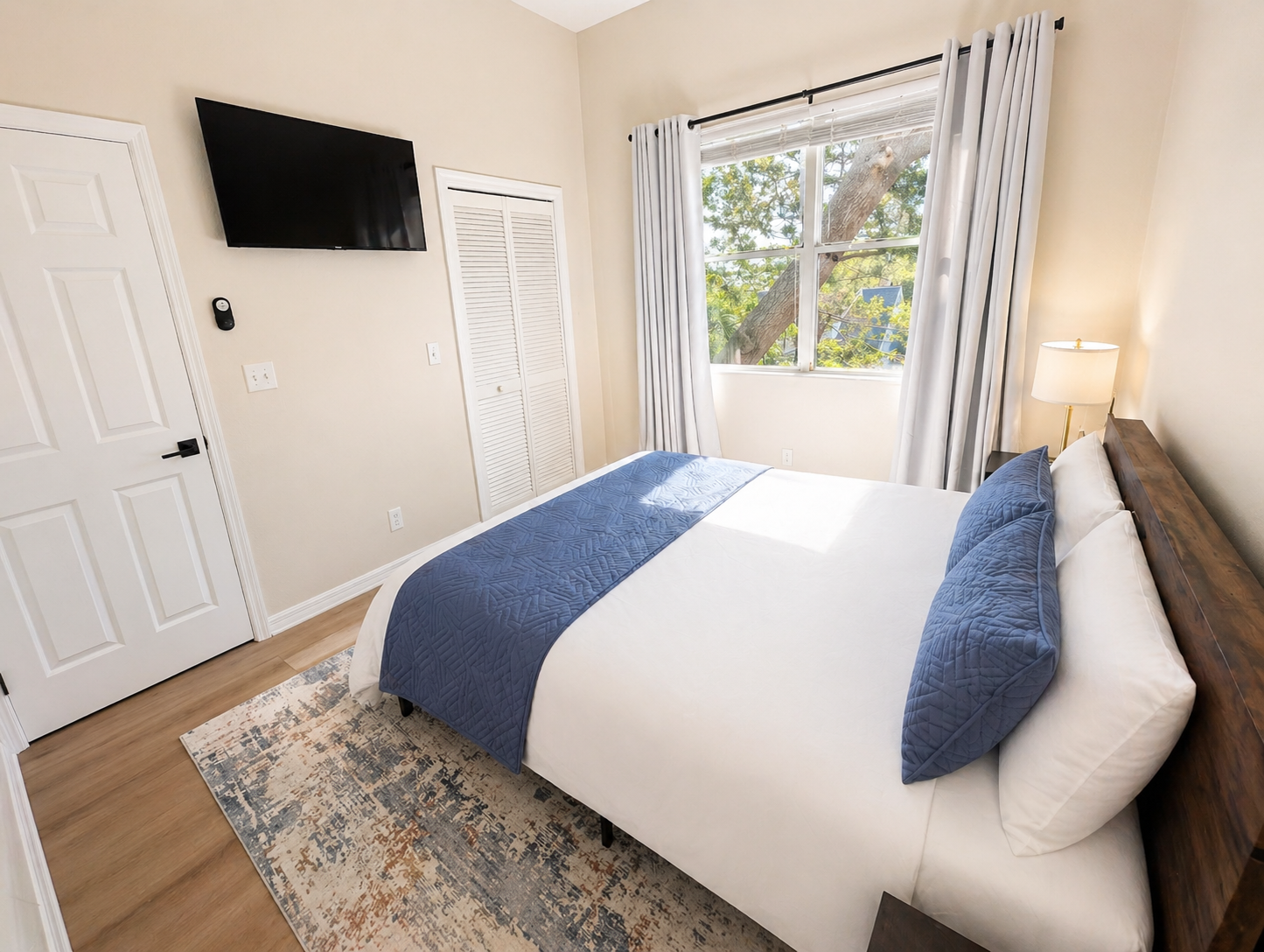 Bright and peaceful bedroom with a comfortable bed, soft linens, and warm wood accents. Large window brings in natural light, while bedside tables and lamps create a cozy, relaxing space for restful nights.