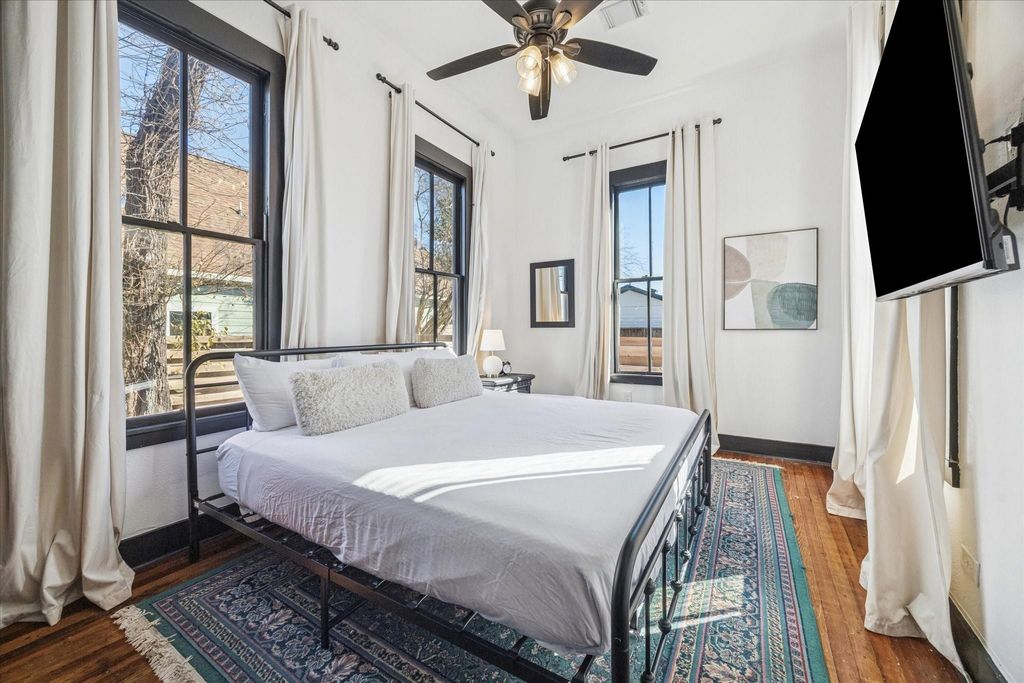 This charming bedroom blends period character with everyday comfort, featuring original hardwood floors, tall ceilings, and tall windows that fill the space with natural light. Its flexible layout easily adapts to guest accommodations, a home office, or a