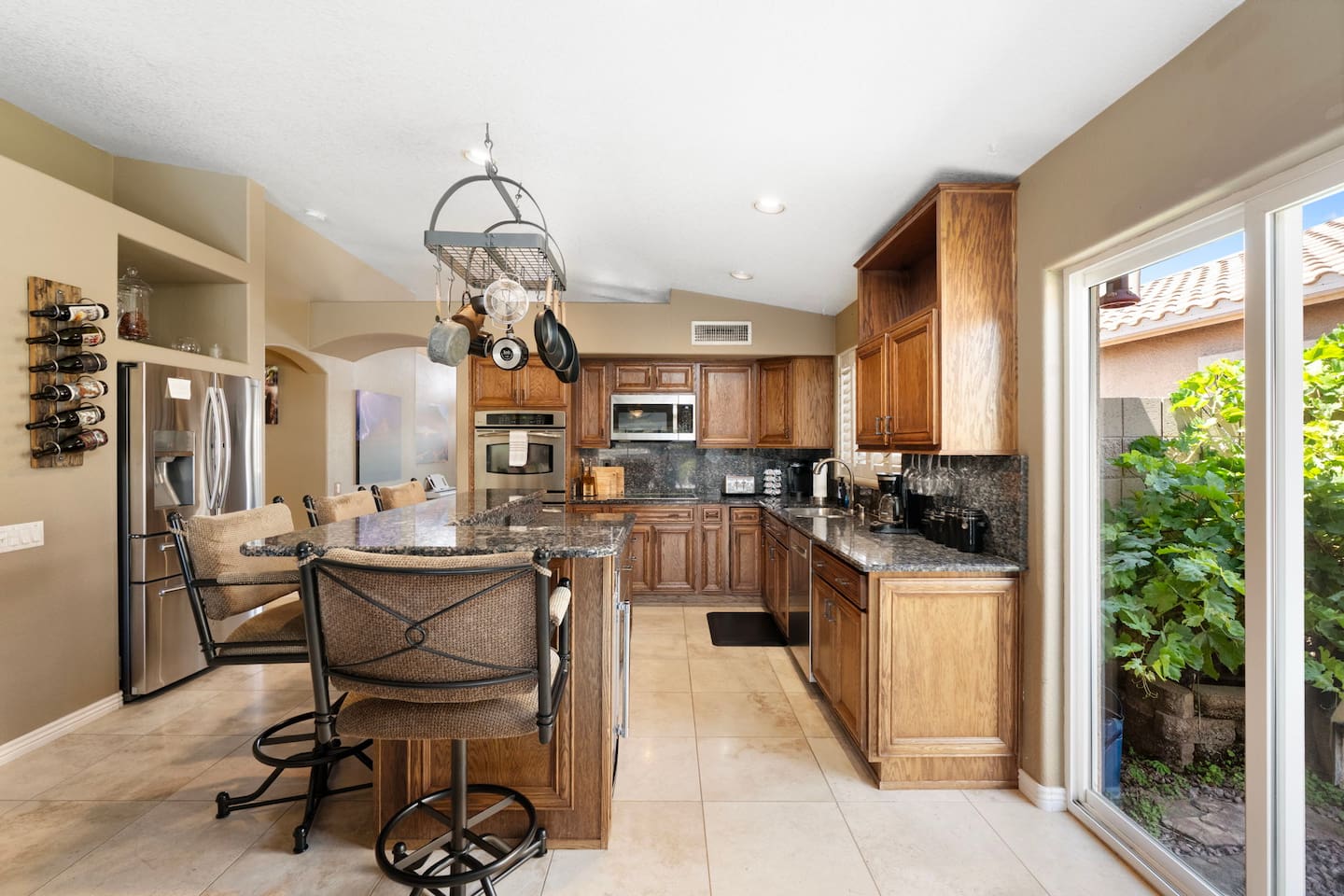A chef's dream kitchen featuring granite countertops, stainless steel appliances, a breakfast bar, and a wall-mounted wine rack — everything you need for home-cooked meals.