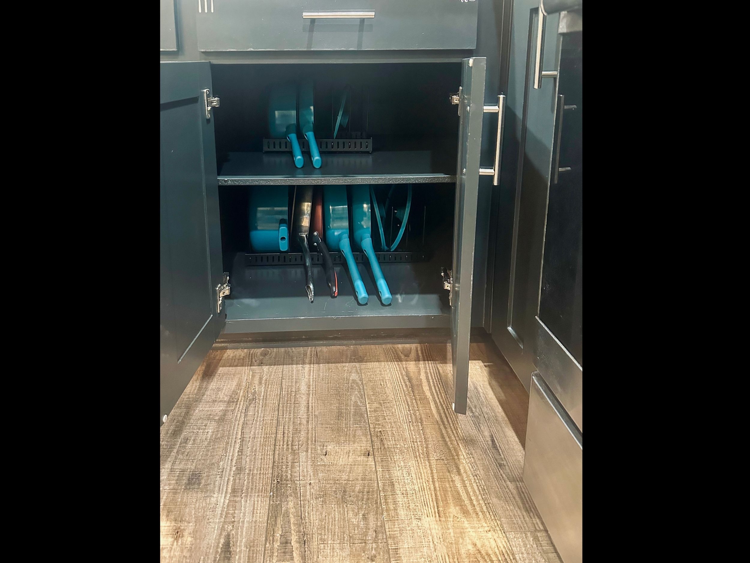 Kitchen cabinet organized with a full set of pots and pans to support everyday cooking and extended stays.