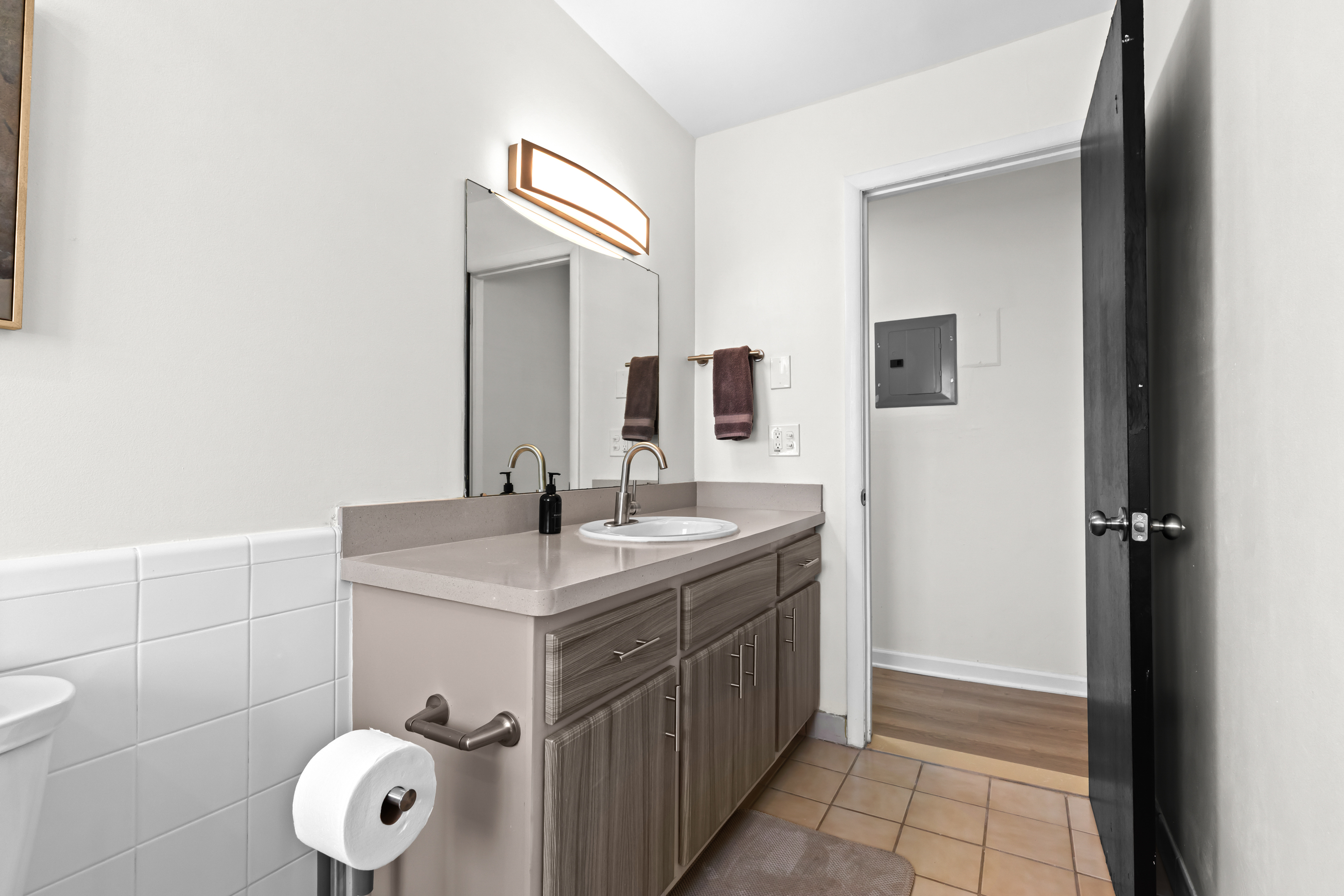 Clean bathroom with a wide vanity, large mirror, and bright lighting.