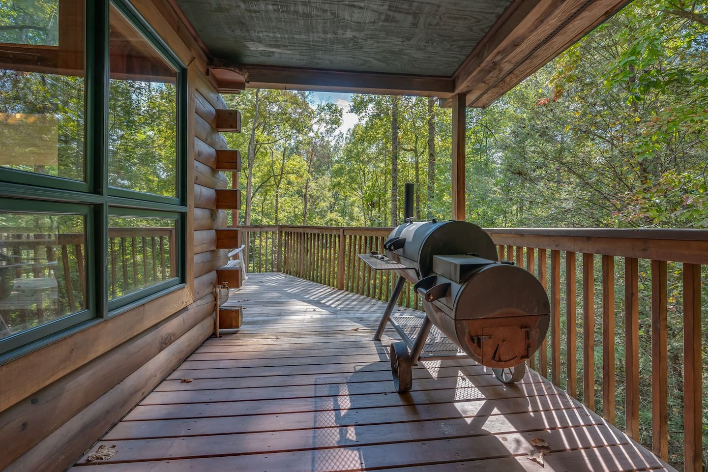 Side deck with large charcoal frill/smoker/log picnic table and corn hole games