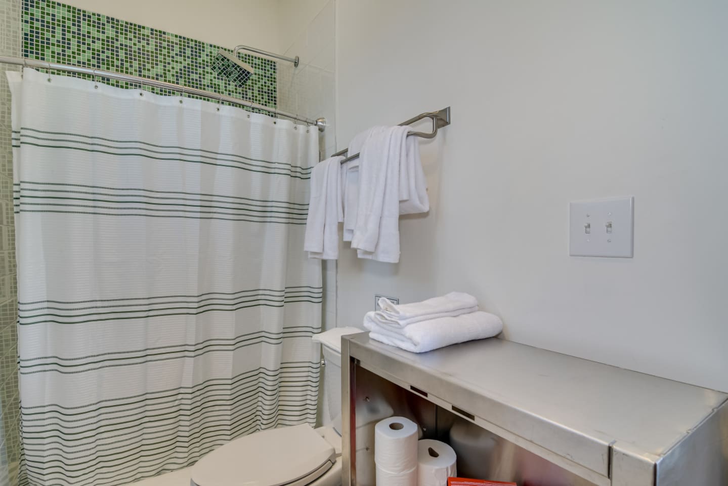 Bathroom with patterned shower curtain and fresh towels.