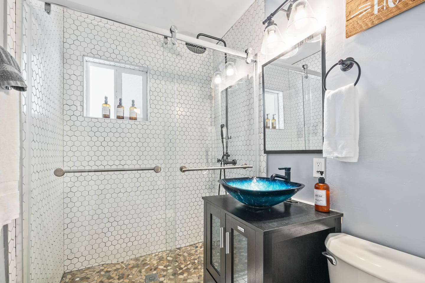Refresh in a modern bathroom featuring a unique sink and a spacious walk-in shower. This stylish setup combines elegance and functionality, creating the perfect space for relaxation during your stay!