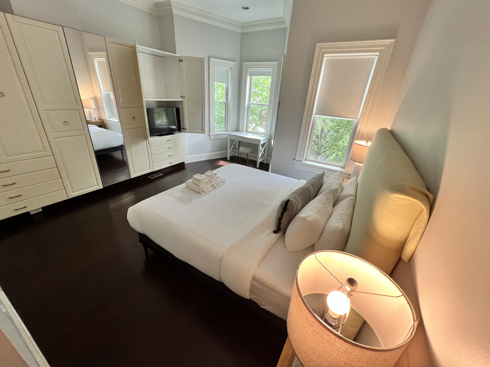 Spacious main bedroom with a newly upgraded plush Serta king bed, tranquil tree-lined views, a 40" Samsung 4K Smart TV, and a bright corner desk—ideal for work or planning your day in DC.