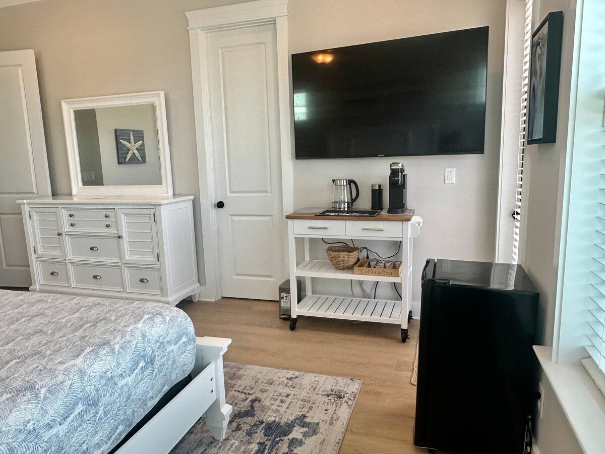 The first-floor primary bedroom offers added convenience with a private coffee bar and mini fridge, perfect for slow mornings or late-night refreshments.