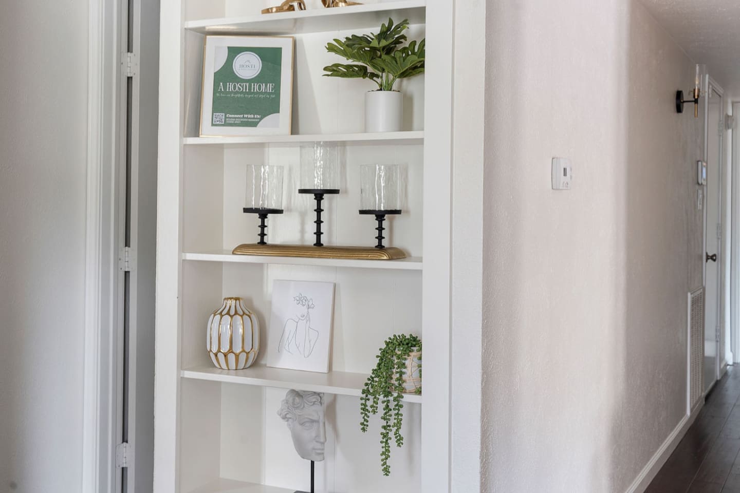Discover elegance in this hallway with a built-in shelf displaying tasteful decor pieces. The greenery and art create a sophisticated ambiance.