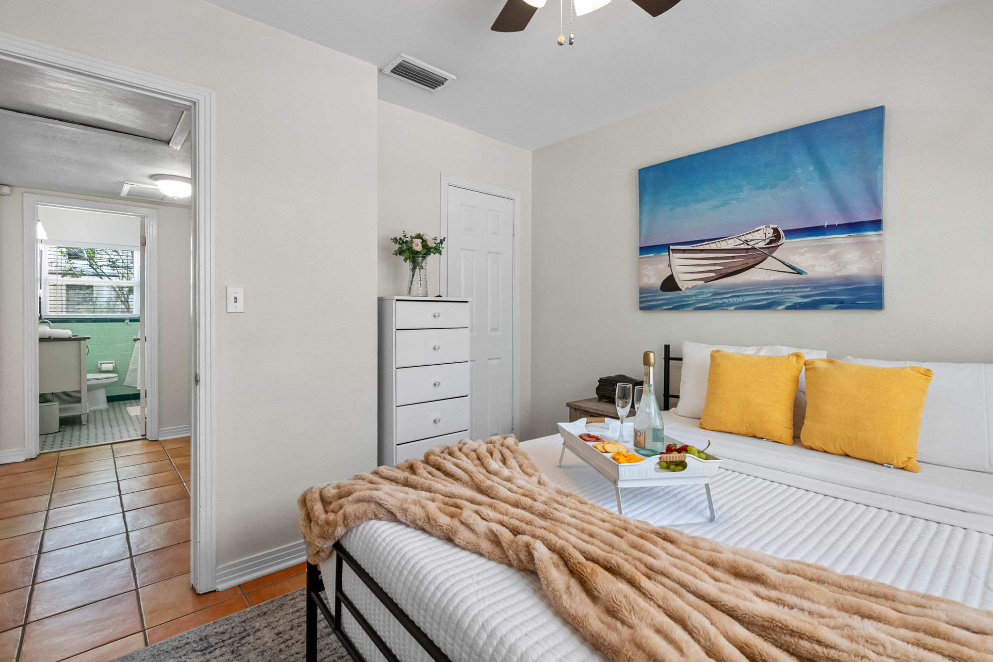 At the center of the room is a sleek, queen-size bed with a minimalist black metal frame and a supportive mattress dressed in crisp, hotel-quality linens.