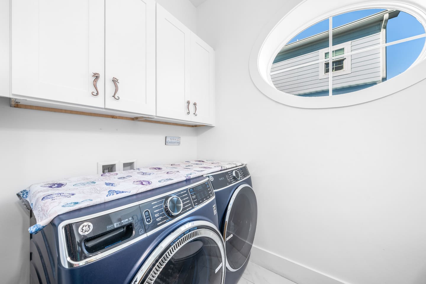 Main-floor half-bath beside kitchen and backyard, features a unique designer shell sink and bespoke 18th-century cabinetry , unique seahorse handles. Equipped with washer/dryer, iron, and beach towels—convenience meets 30A coastal style.