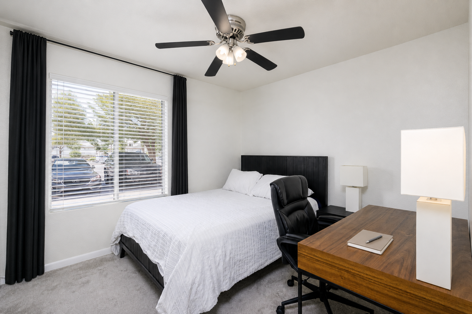 Bedroom with queen bed, dedicated desk, ceiling fan, and natural light for work or rest.