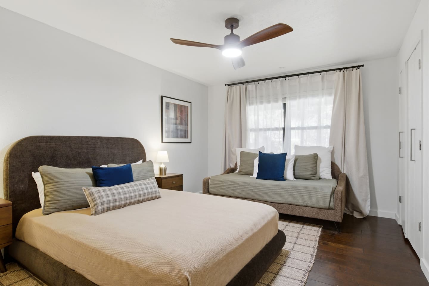 Flexible guest bedroom with both a queen and a twin bed, featuring room-darkening shades and plush bedding to comfortably accommodate families, kids, or mixed groups during their stay.