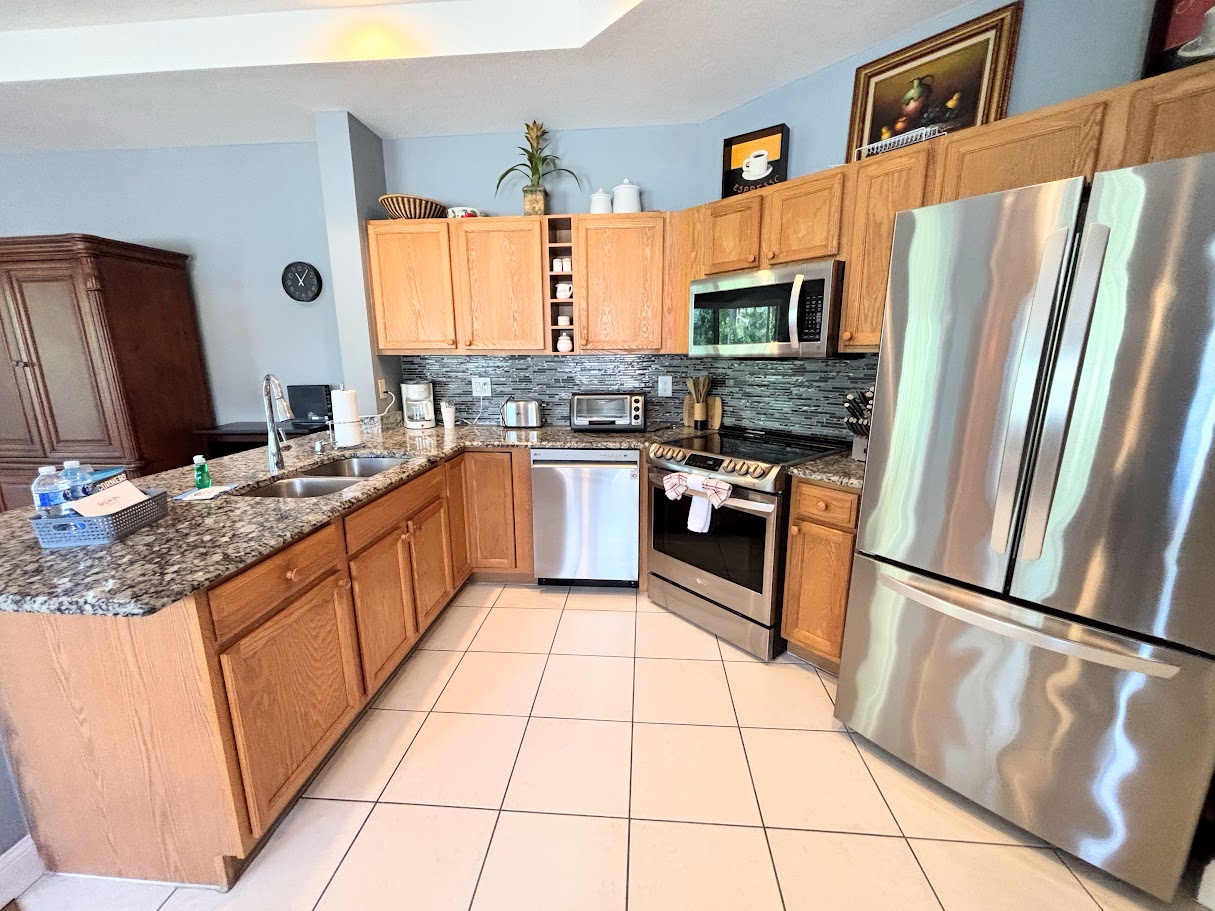 Fully equipped kitchen with stainless steel appliances, granite countertops, tile flooring, and plenty of cabinet space.
