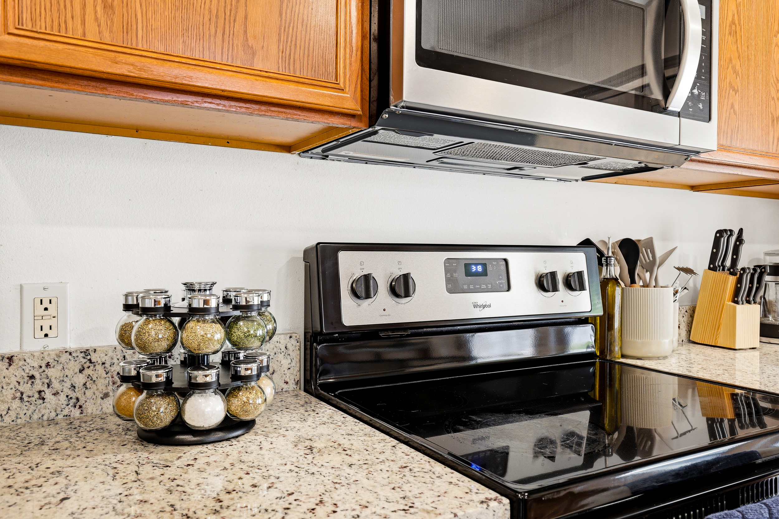 Electric stove with spice rack, over-range microwave, and full set of cooking utensils ready to go. Granite countertops and ample prep space make this kitchen easy to cook in for the whole group.