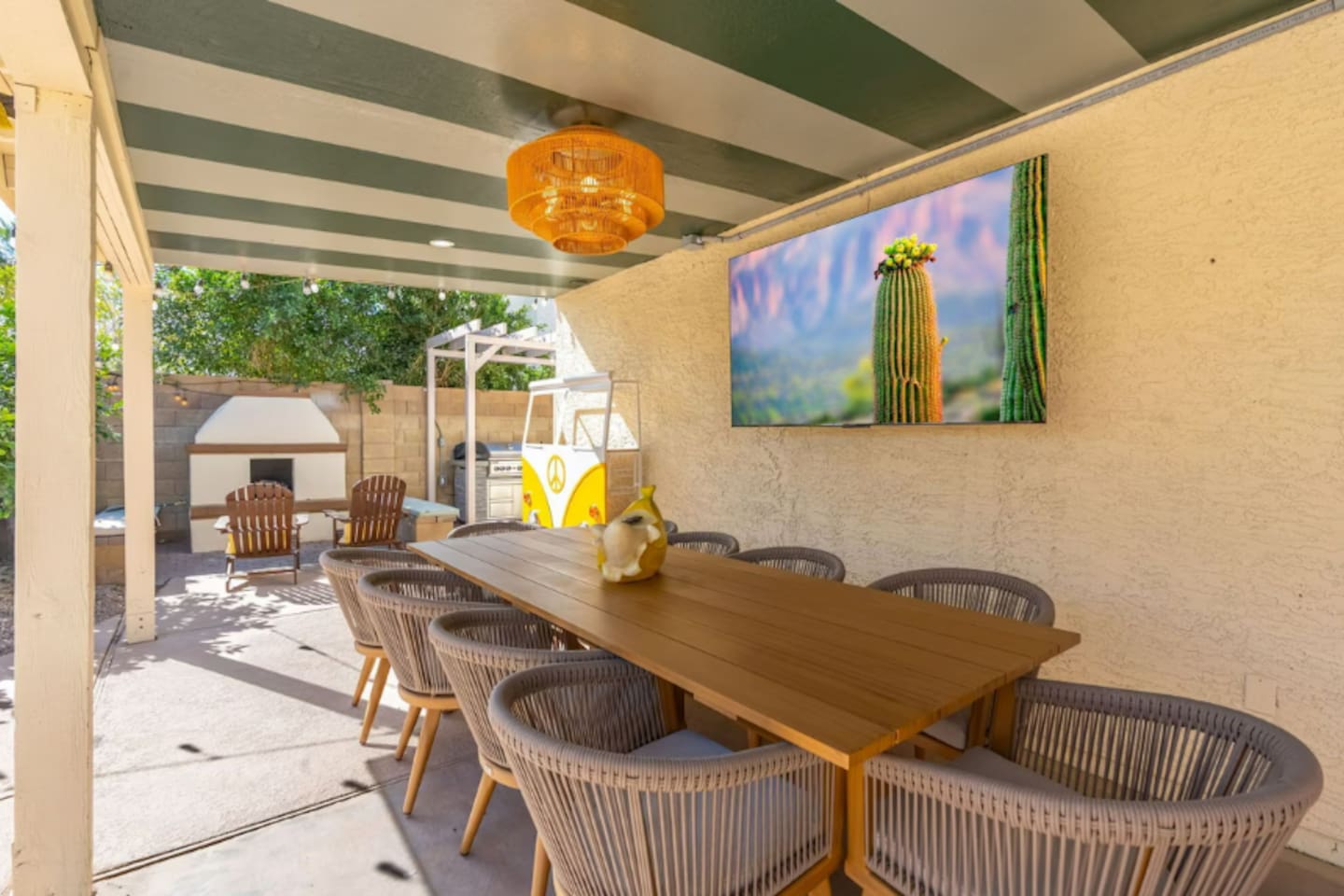 Spacious covered patio with striped ceiling, dining table, desert art, and direct pool access—seamless indoor-outdoor entertaining.