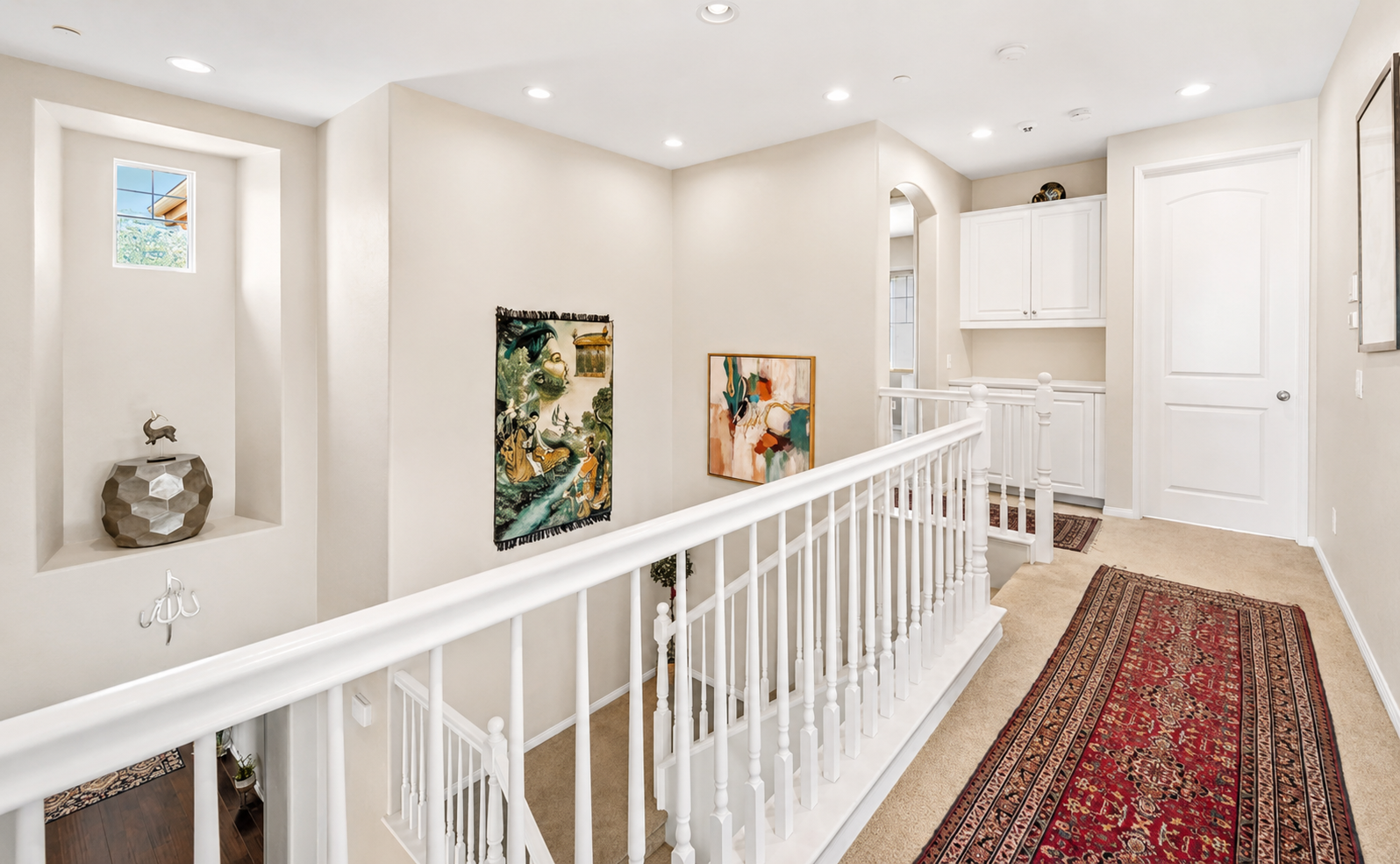 Upstairs landing with clean railings, artwork, and a hallway connecting the bedrooms.