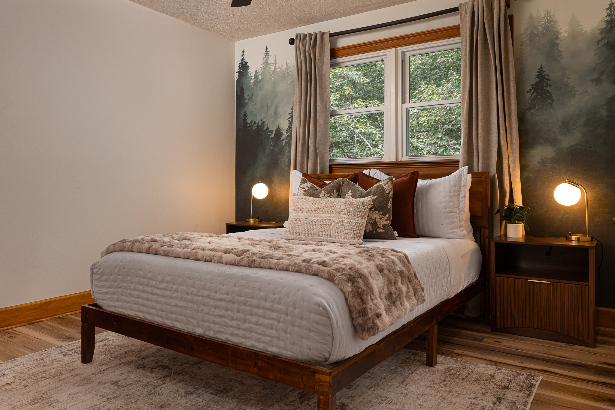 {Bedroom 2} A peaceful queen bedroom with a forest-inspired mural, warm textures, and windows overlooking the trees.
