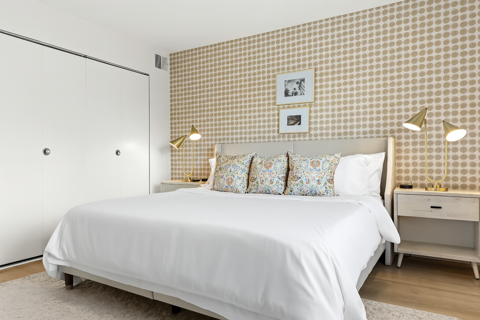Inviting king bedroom with patterned accent wall, bedside lighting, and soft, neutral tones.